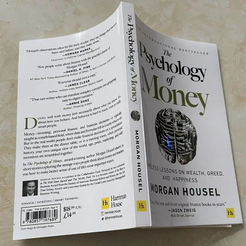 Open book titled 'The Psychology of Money' by Morgan Housel on a light surface.