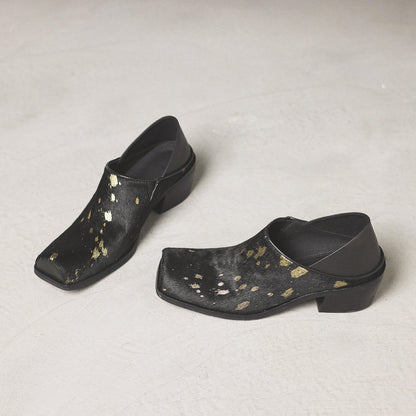 Pair of black clogs with gold speckles on a light gray background