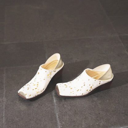 Pair of white clogs with gold speckles on a dark gray surface