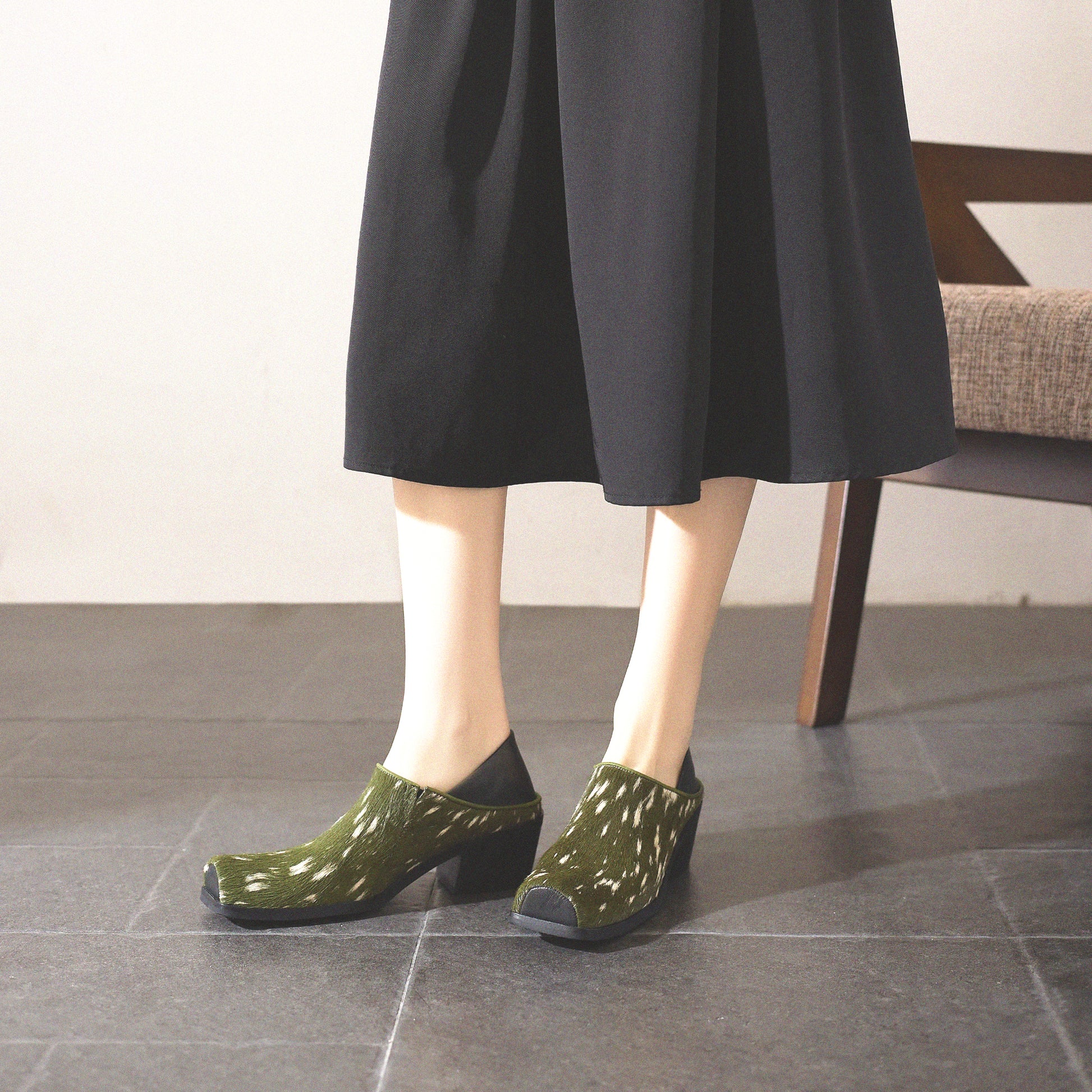Person wearing green patterned shoes on a tiled floor.